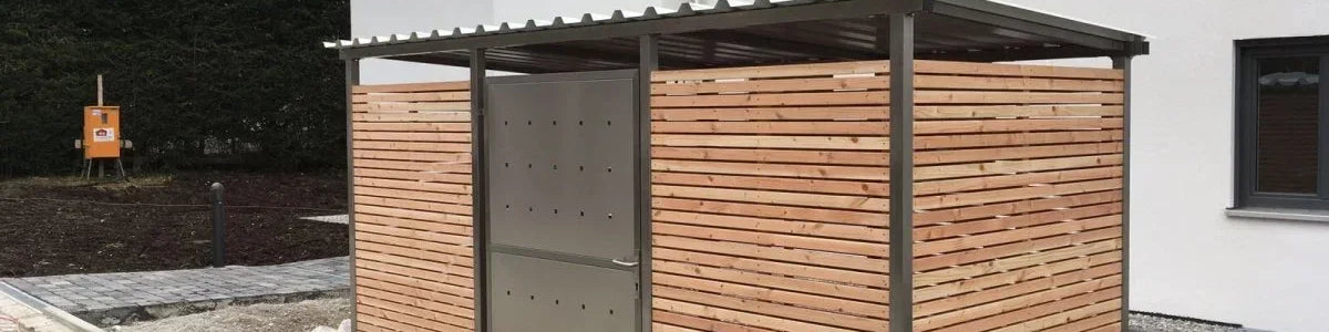 Mülltonnenhaus aus Holz mit Metallrahmen und Flachdach vor modernem Wohnhaus