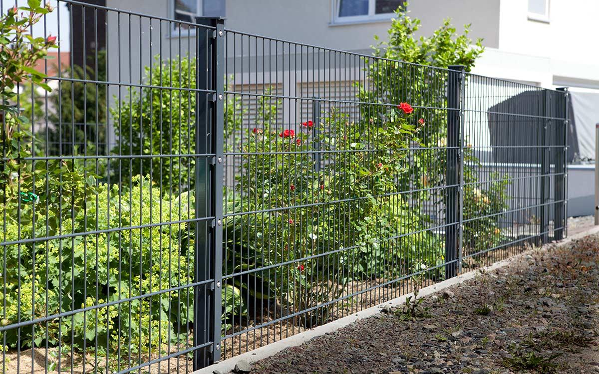 Doppelstabmattenzaun anthrazit als Gartenzaun vor bepflanztem Garten an Wohnhaus