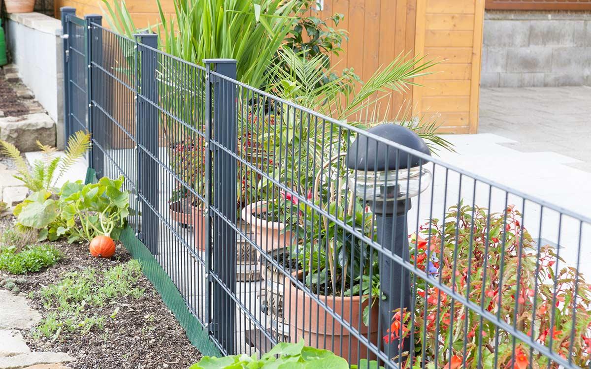 Doppelstabmattenzaun in Anthrazit als Gartenzaun mit Pflanzen und Außenleuchte