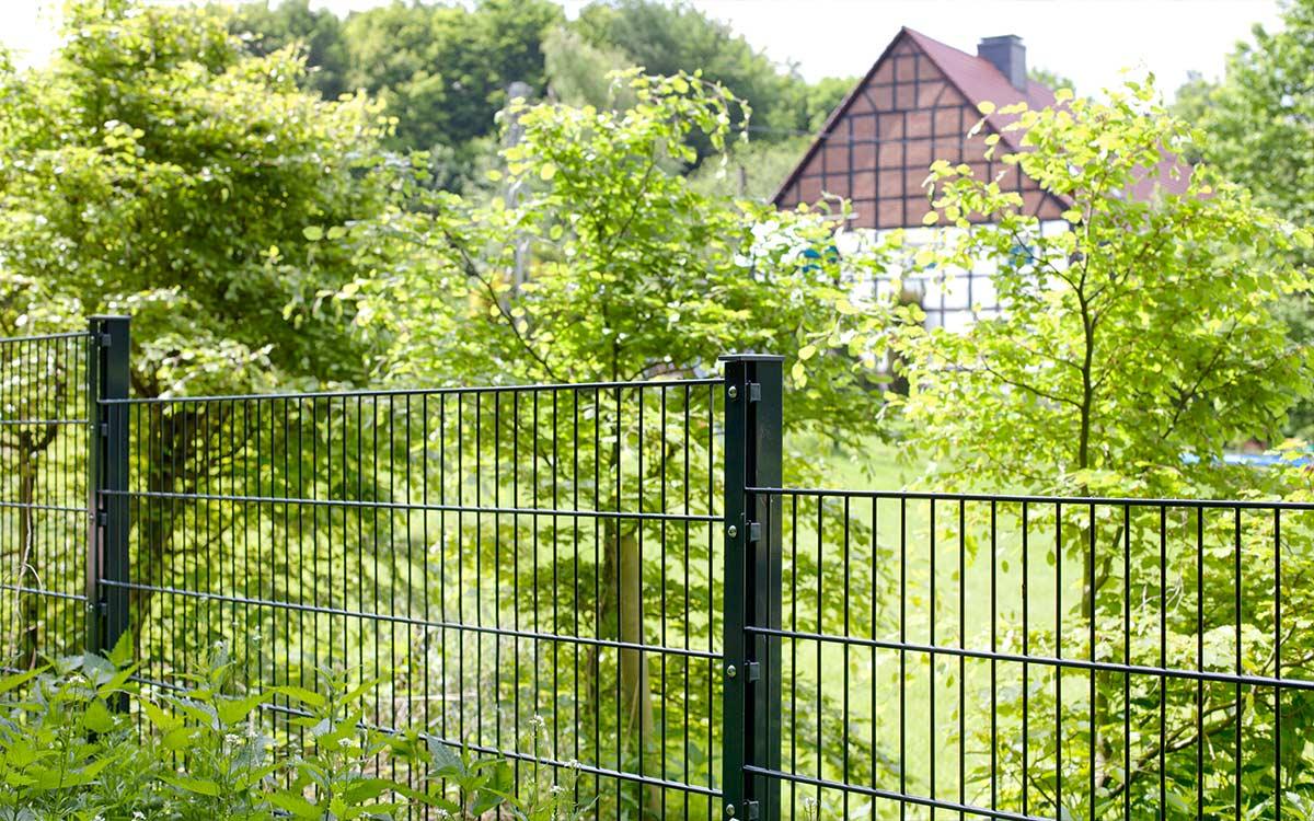 Doppelstabmattenzaun 6/5/6 Modell PICO als Gartenzaun vor grünen Bäumen