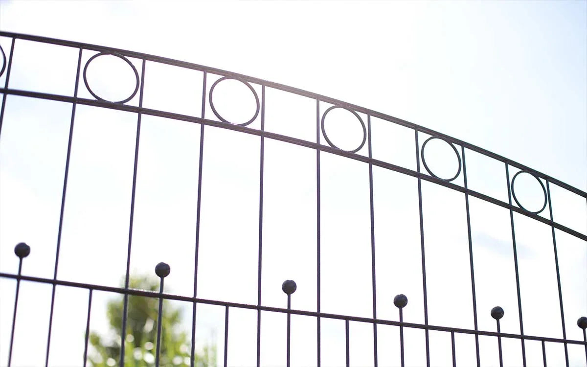 Moderner Doppelstabmattenzaun aus Metall mit Zierelementen und Kreisornamenten im Freien