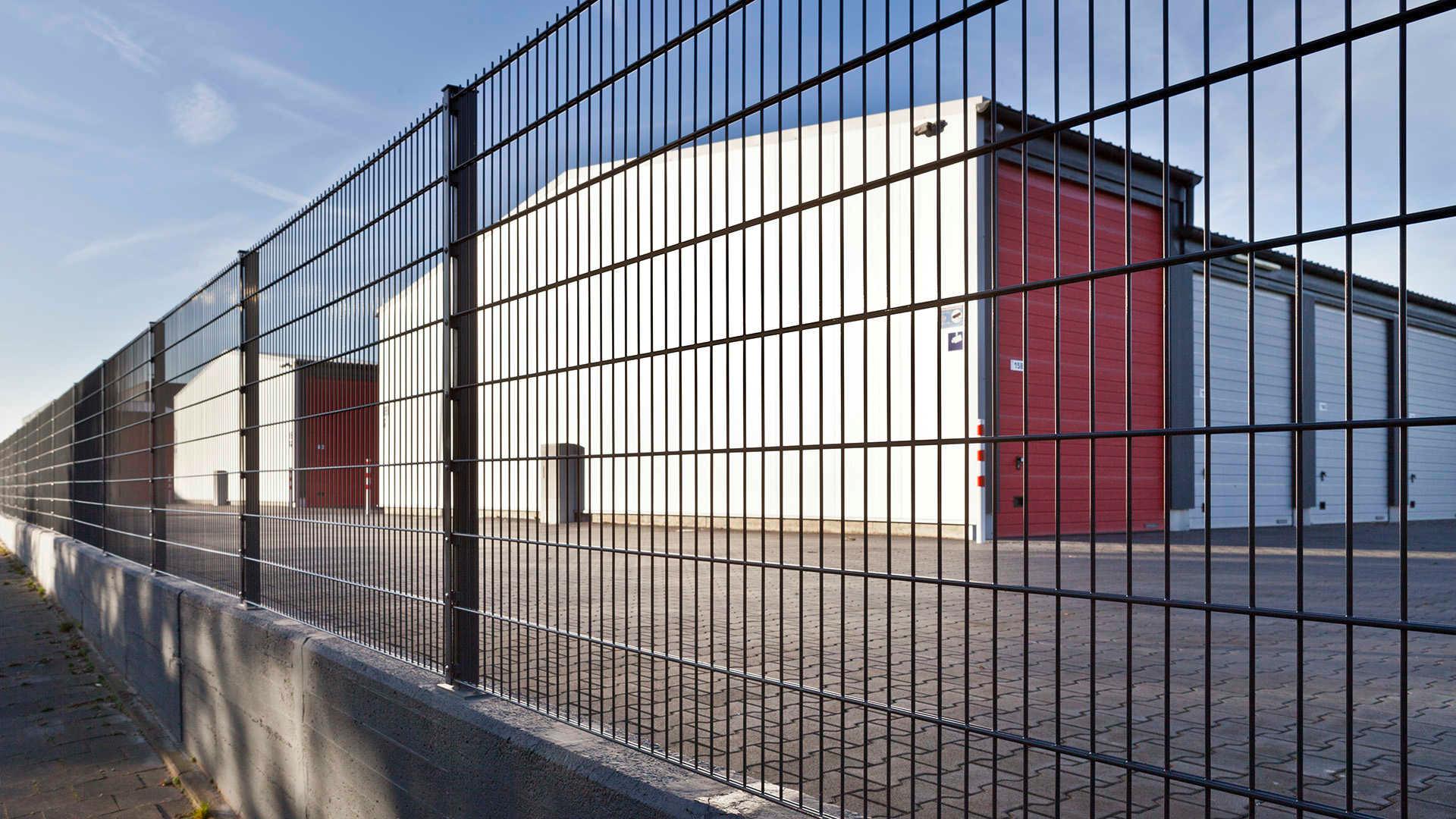 Doppelstabmattenzaun 8/6/8 vor Industriegebäude mit rotem Tor, Sichtschutzzaun Gewerbe
