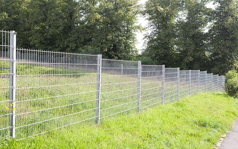 Doppelstabmattenzaun 8/6/8 verzinkt als Gartenzaun vor grüner Wiese und Bäumen
