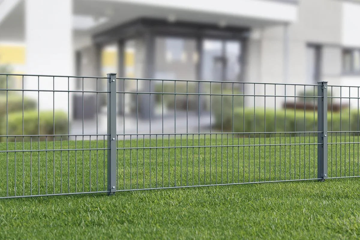 Doppelstabmattenzaun aus Metall auf grünem Rasen vor modernem Gebäude