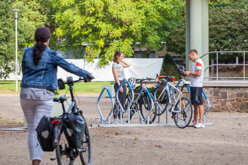 Fahrradparker aus Metall im Freien, mehrere Fahrräder und Personen am Fahrradständer