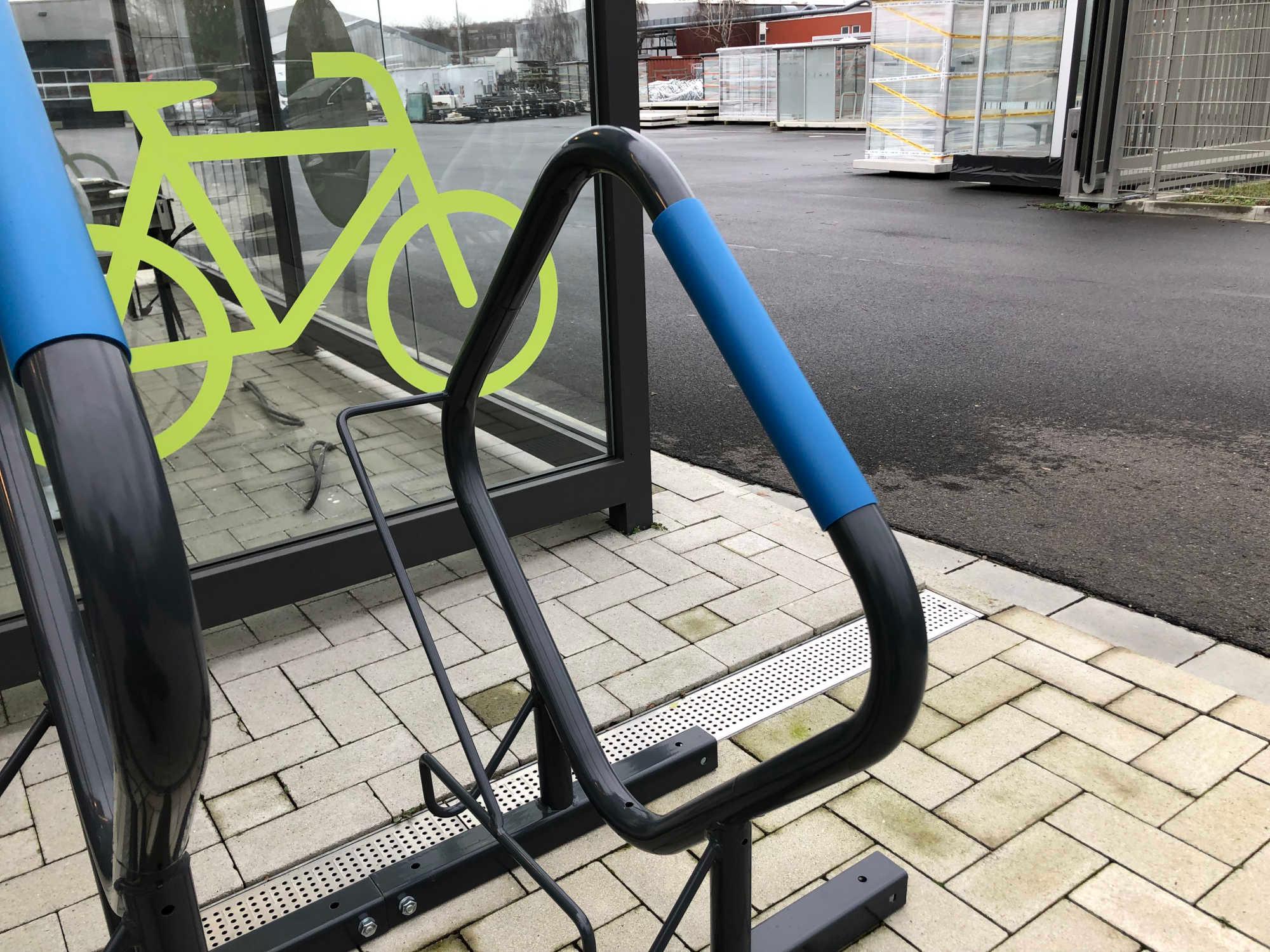 Moderner Fahrradständer aus Metall mit blauen Polstern auf gepflastertem Außenbereich