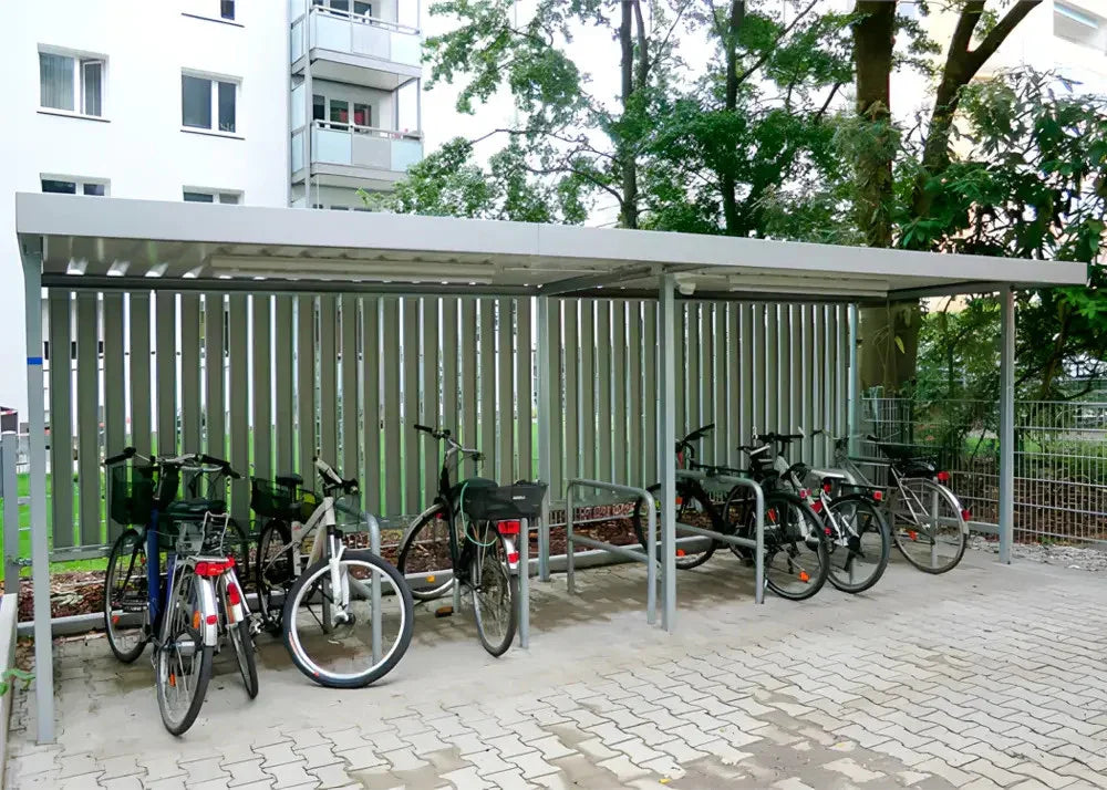 Moderne Fahrradüberdachung aus Metall mit mehreren abgestellten Fahrrädern in Wohnanlage