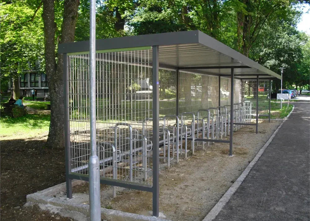 Moderne Fahrradüberdachung aus Metall mit Fahrradständern im Park neben Gehweg