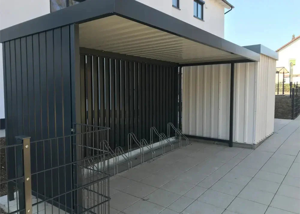 Moderne Fahrradüberdachung aus Metall mit Fahrradständern vor einem Wohngebäude