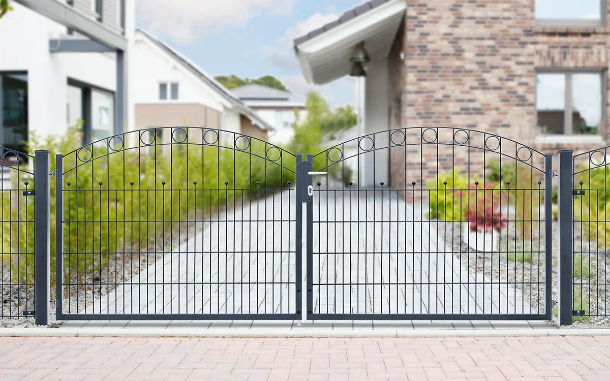 Doppelflügeliges Metall-Gartentor mit dekorativen Kreisen vor moderner Einfahrt