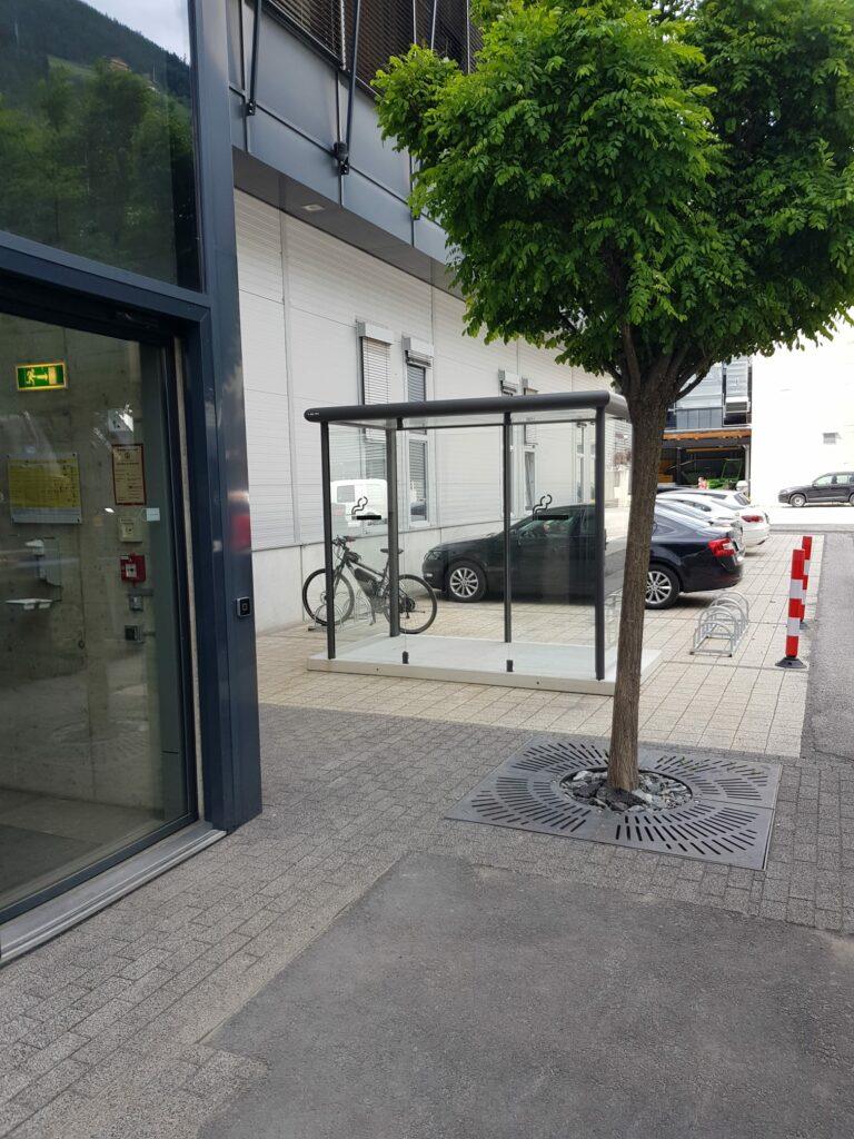 Moderne Raucherkabine aus Glas und Metall im Außenbereich vor Firmengebäude