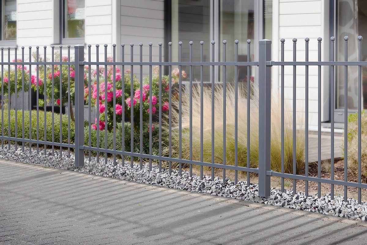 Moderner Metallzaun grau vor Haus mit Blumenbeet und Zierkies im Vorgarten