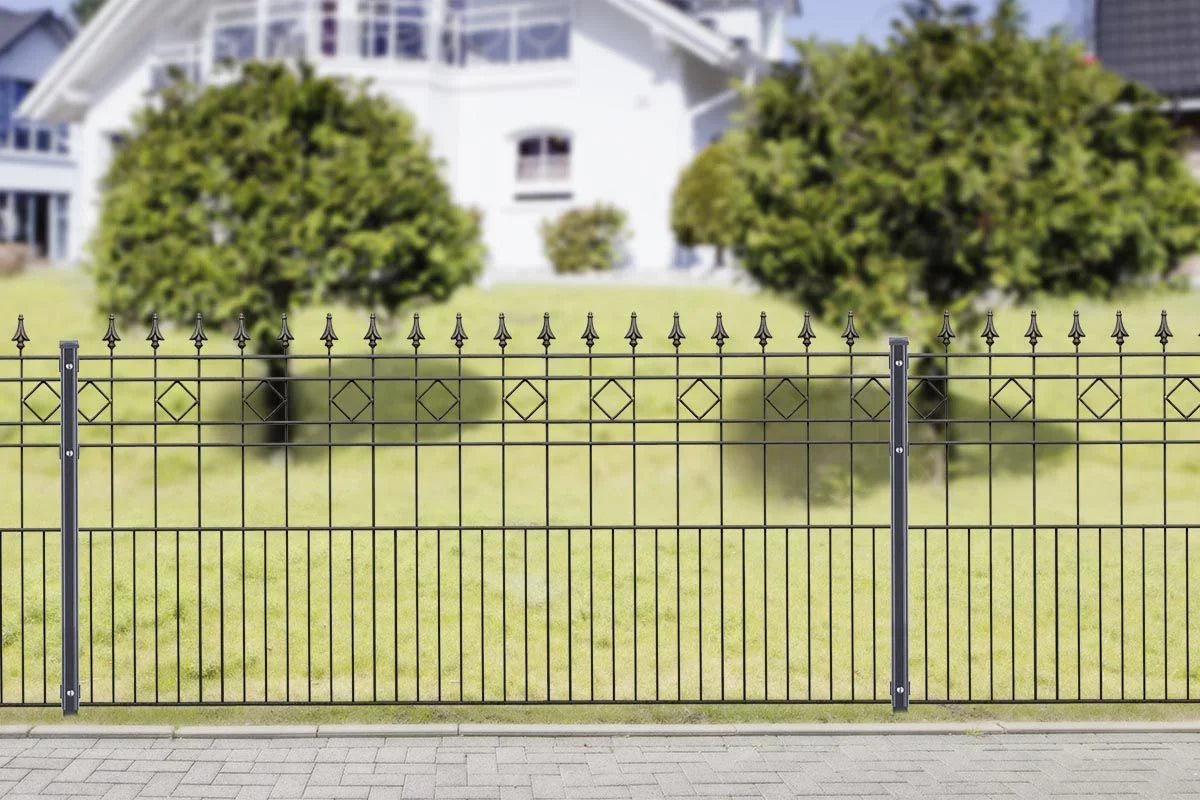 Moderner Metallzaun mit Spitzenornamenten und geometrischem Muster vor einem Garten