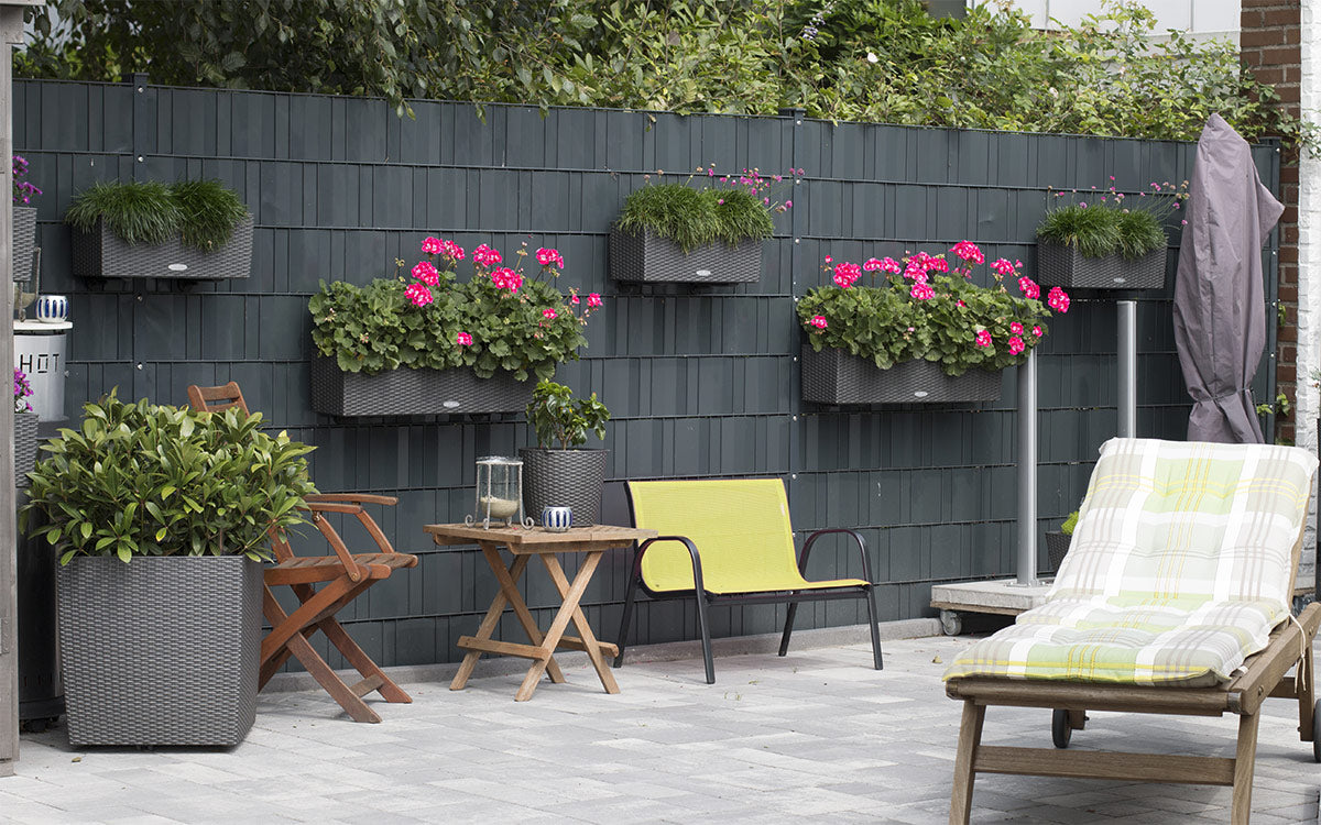 Sichtschutzzaun als Terrassenabtrennung mit Blumenkästen und Gartenmöbeln