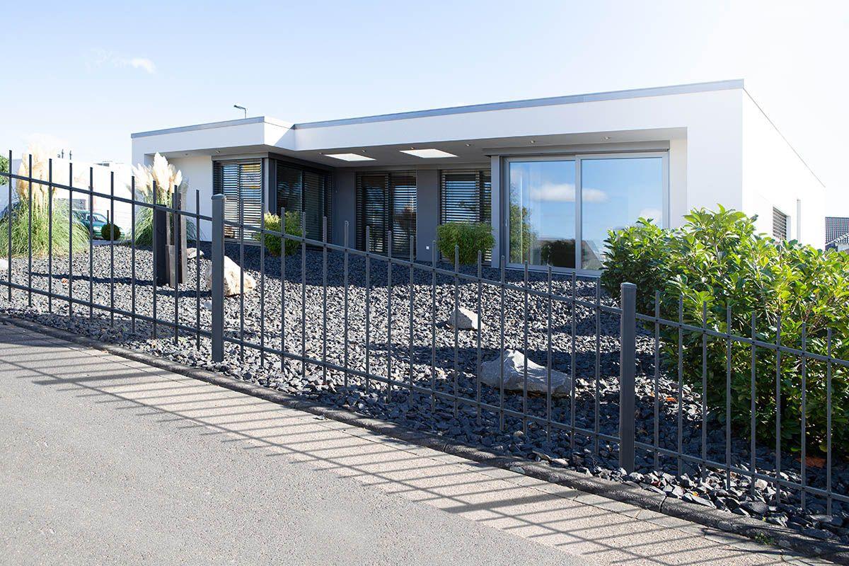 Moderner Metall-Steigungszaun vor Einfamilienhaus mit Schottergarten und Begrünung