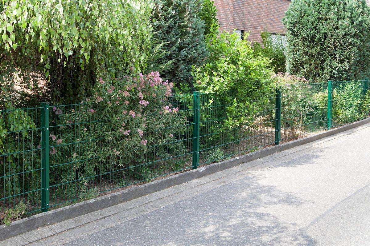 Grüner Metallzaun Typ VAP am Straßenrand mit Büschen und Blumen im Garten