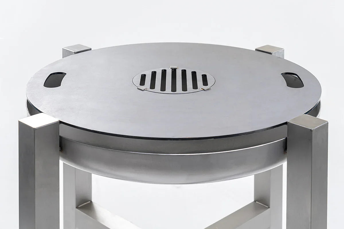 Edelstahlgrill und Feuerschale mit runder Grillplatte und modernem Design auf hellem Hintergrund