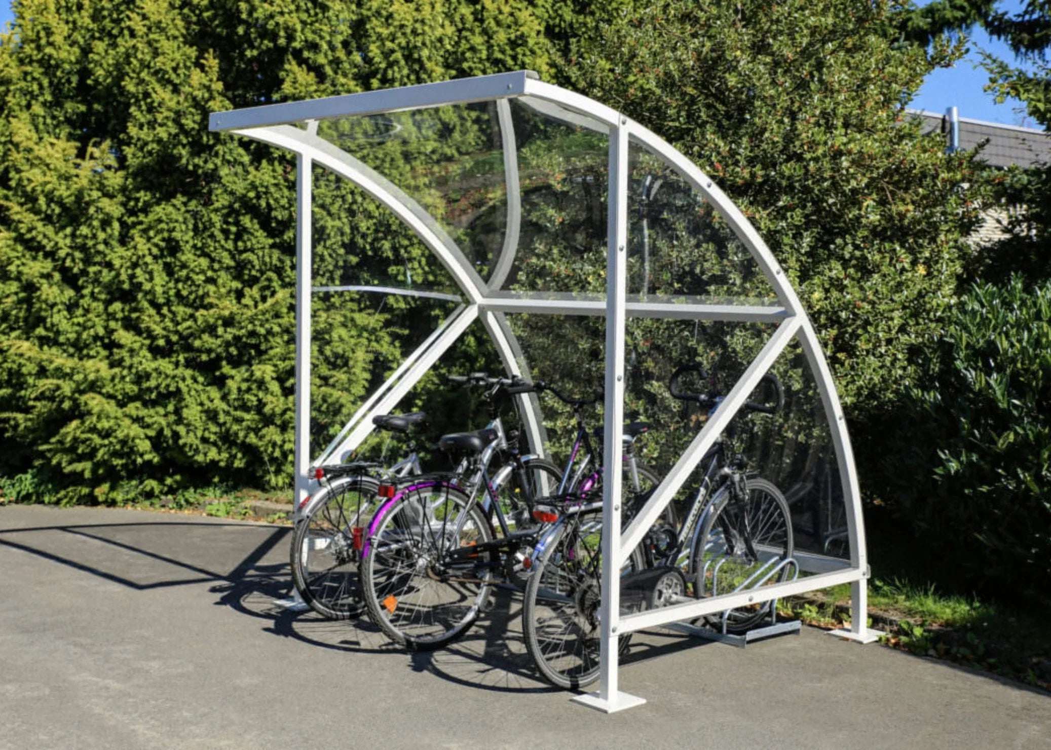 Moderner Fahrradunterstand aus Metall und Glas mit mehreren abgestellten Fahrrädern im Freien