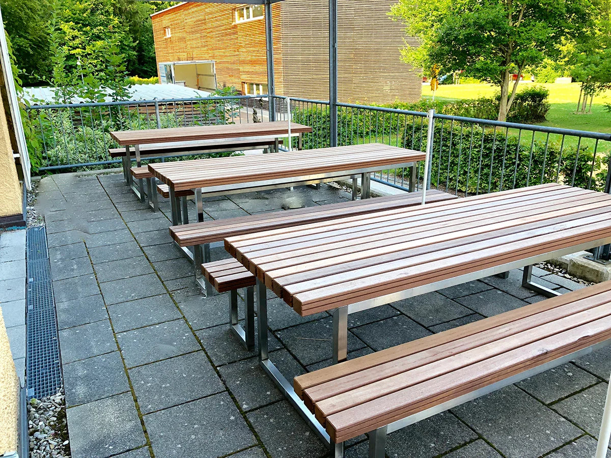 Gartentische und Gartenbänke aus Metall-Holz-Kombination auf einer Terrasse