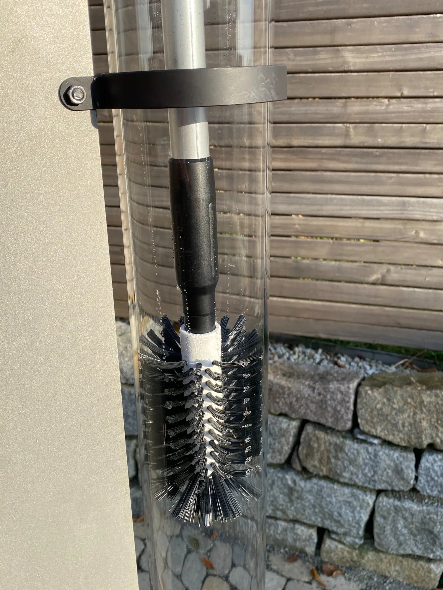Glasreinigungsbürste mit schwarzem Griff in transparenter Halterung im Außenbereich