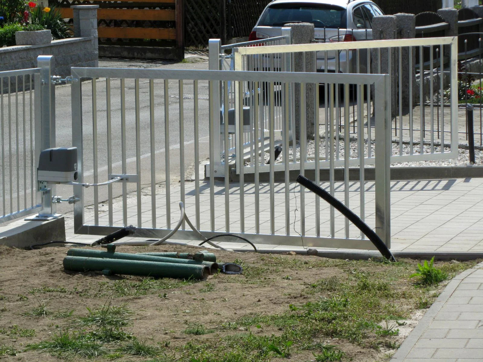 Silbernes Metall Hoftor mit elektrischem Antrieb auf gepflasterter Einfahrt