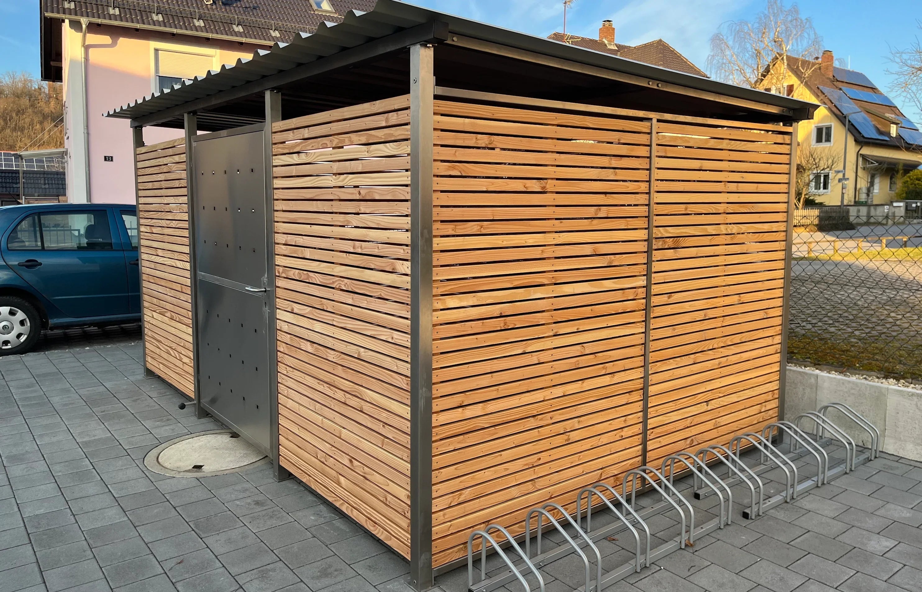 Moderne Mülltonnenbox aus Edelstahl und Holz mit Flachdach und integriertem Fahrradständer