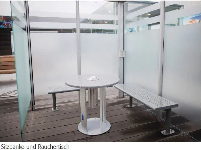 Raucherkabine aus Metall mit zwei Sitzbänken und rundem Rauchertisch auf Holzboden