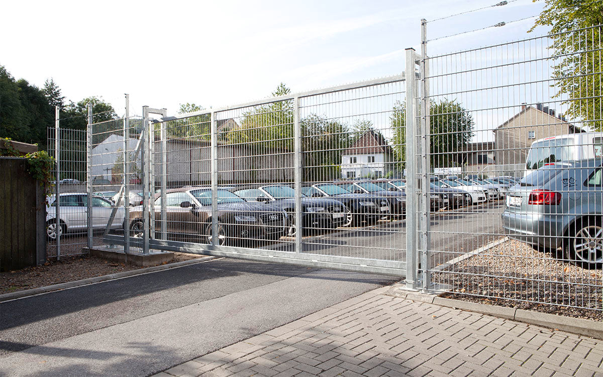Schiebetor EasyStar feuerverzinkt an einer Parkplatzzufahrt, Zaun mit Übersteigschutz nicht im Lieferumfang