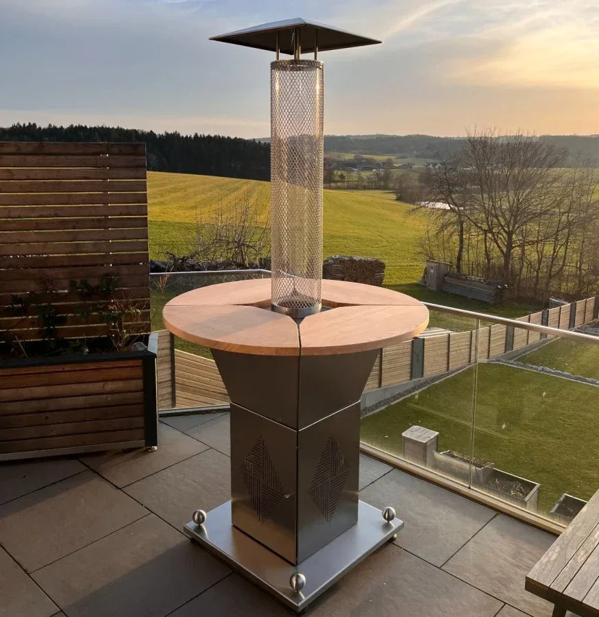 Moderner beheizter Stehtisch mit Pellet-Heizstrahler auf Terrasse bei Sonnenuntergang