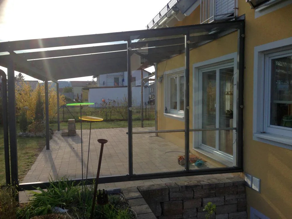 Moderne Terrassenüberdachung aus Metall und Glas an Einfamilienhaus im Garten