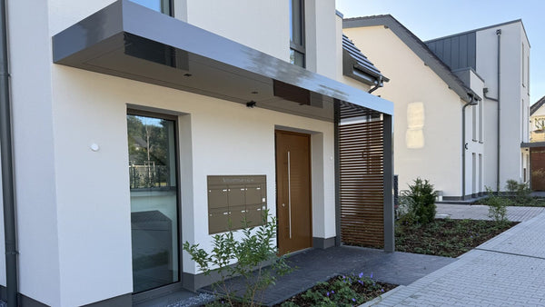 Vordach Platin auf Tragwerk aus Aluminium in Anthrazit über einem Hauseingang mit Lamellen-Sichtschutz