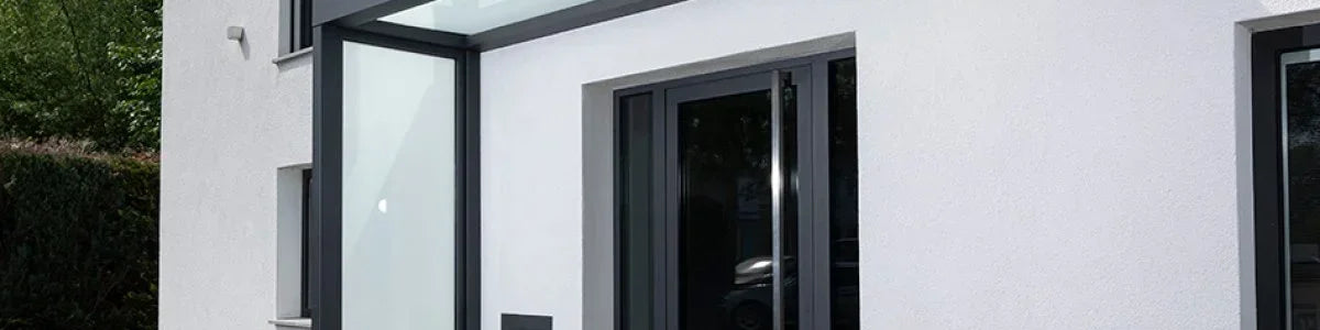 Modernes Vordach aus VSG Glas und Metall an einem Hauseingang, wetterfester Schutz