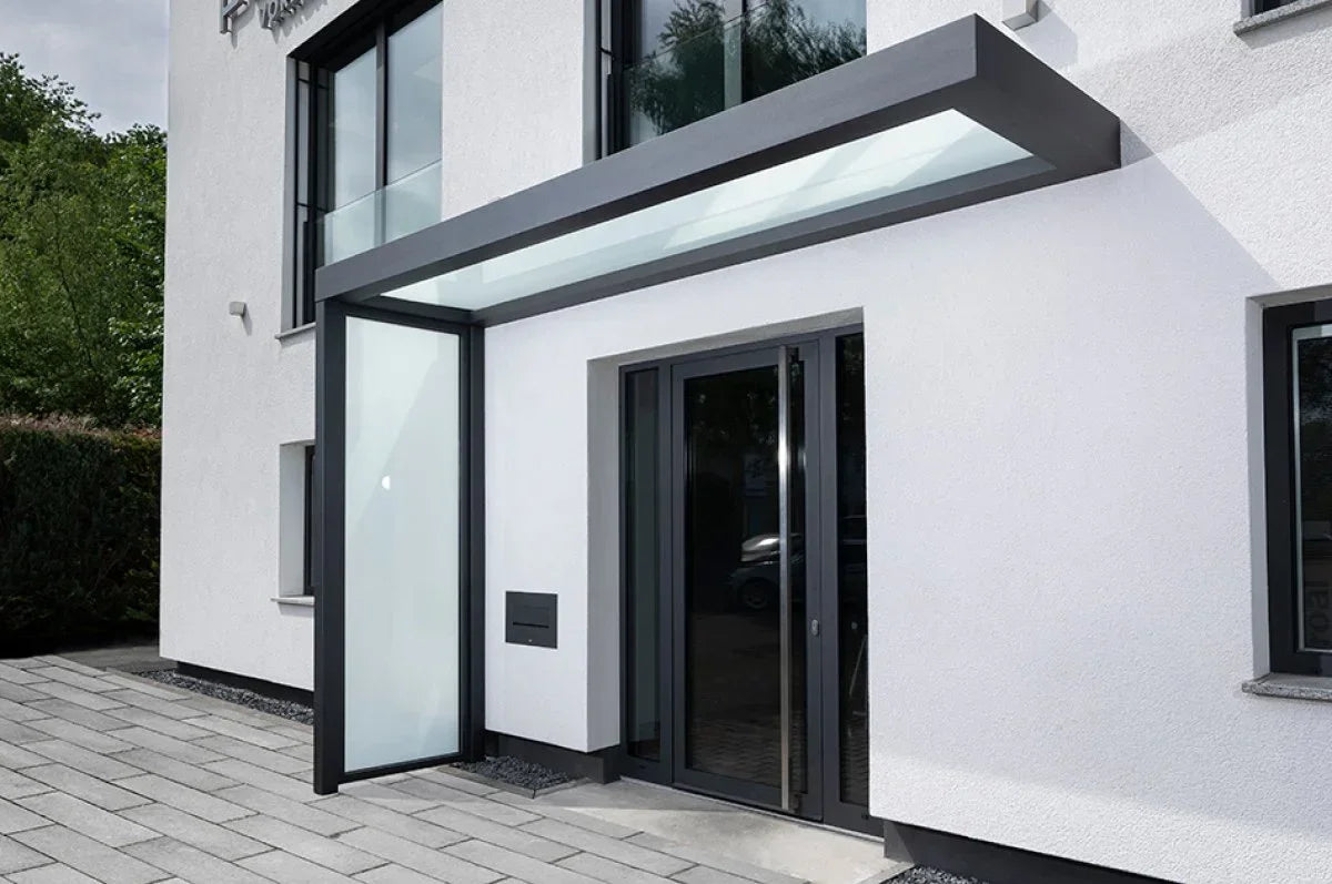 Modernes Vordach aus VSG Glas und Metall an einem Hauseingang, wetterfester Schutz