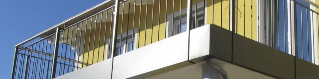 Modernes Balkongeländer aus Metall an gelbem Haus, vertikale Stäbe, klare Linien