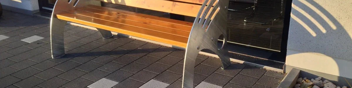 Moderne Gartenbank aus Holz und Metall mit gebogenen Armlehnen auf gepflasterter Terrasse