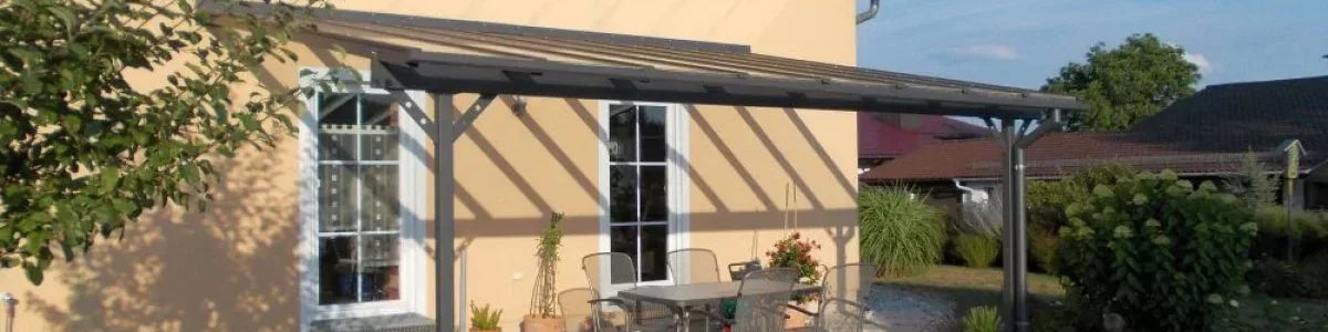 Moderne Terrassenüberdachung aus Metall an Einfamilienhaus mit Gartenmöbeln auf Terrasse