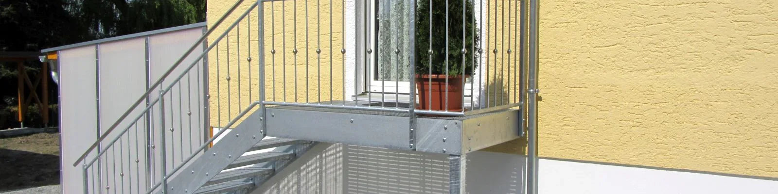 Außentreppe aus Metall mit Geländer an gelber Hauswand, verzinkt, modern, sicher