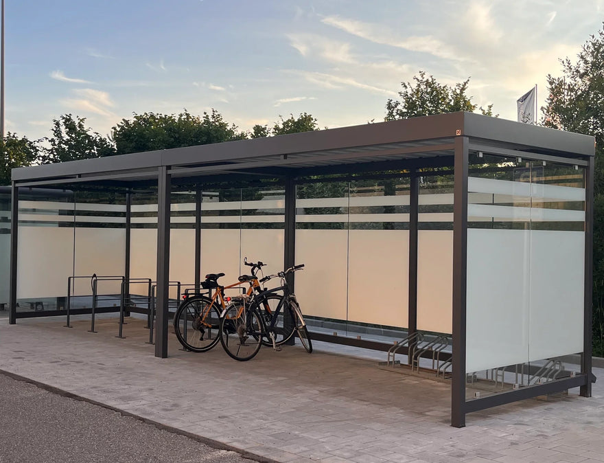 Moderne Fahrradüberdachung aus Metall mit Glaswänden und Fahrradständern im Außenbereich