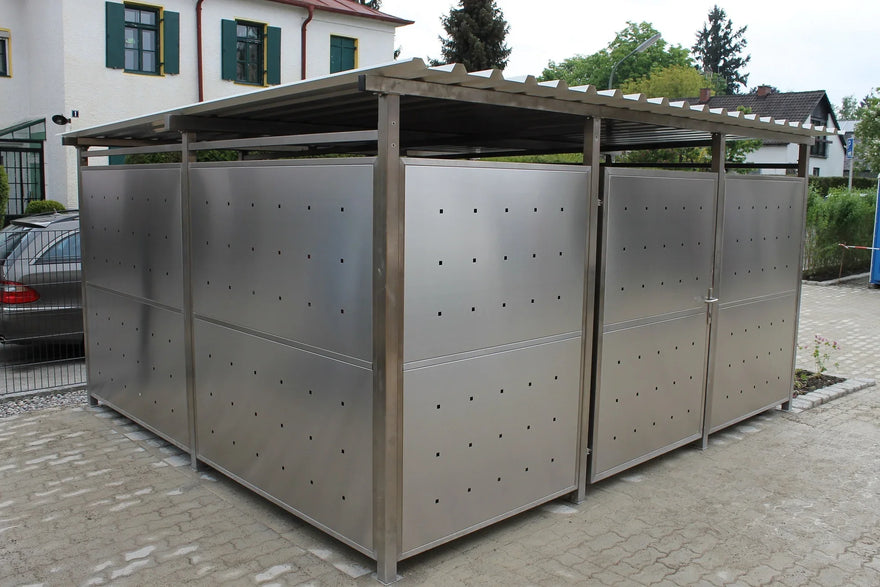 Modernes Containerhaus aus Edelstahl mit Lochblech, Überdachung und Tür, auf gepflastertem Hof