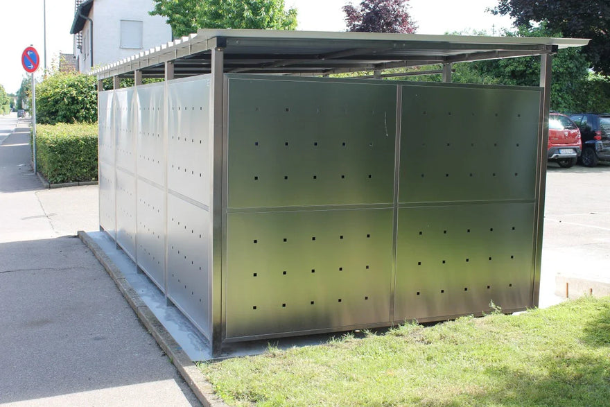 Modernes Mülltonnenhaus aus Metall mit Lüftungsöffnungen, auf Gehweg und Wiese