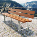 Parkbank aus Fichteholz mit verzinktem Metallgestell auf Steinboden, Berge im Hintergrund