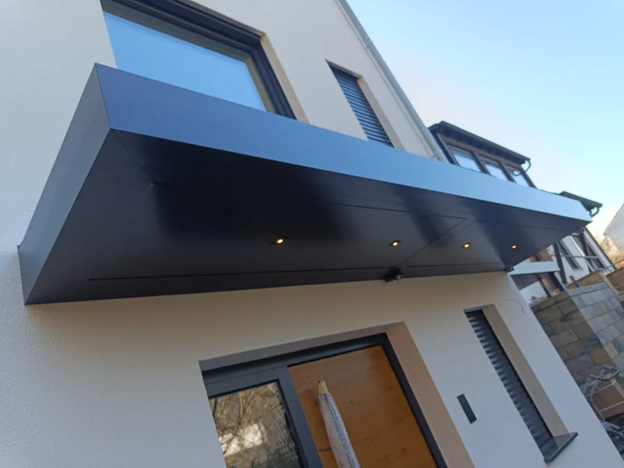 Moderne Haustür Überdachung aus Metall mit integrierter LED-Beleuchtung an Gebäudefassade