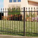 Schmuckzaun aus Metall mit Zierspitzen vor Garten und Haus bei Tageslicht