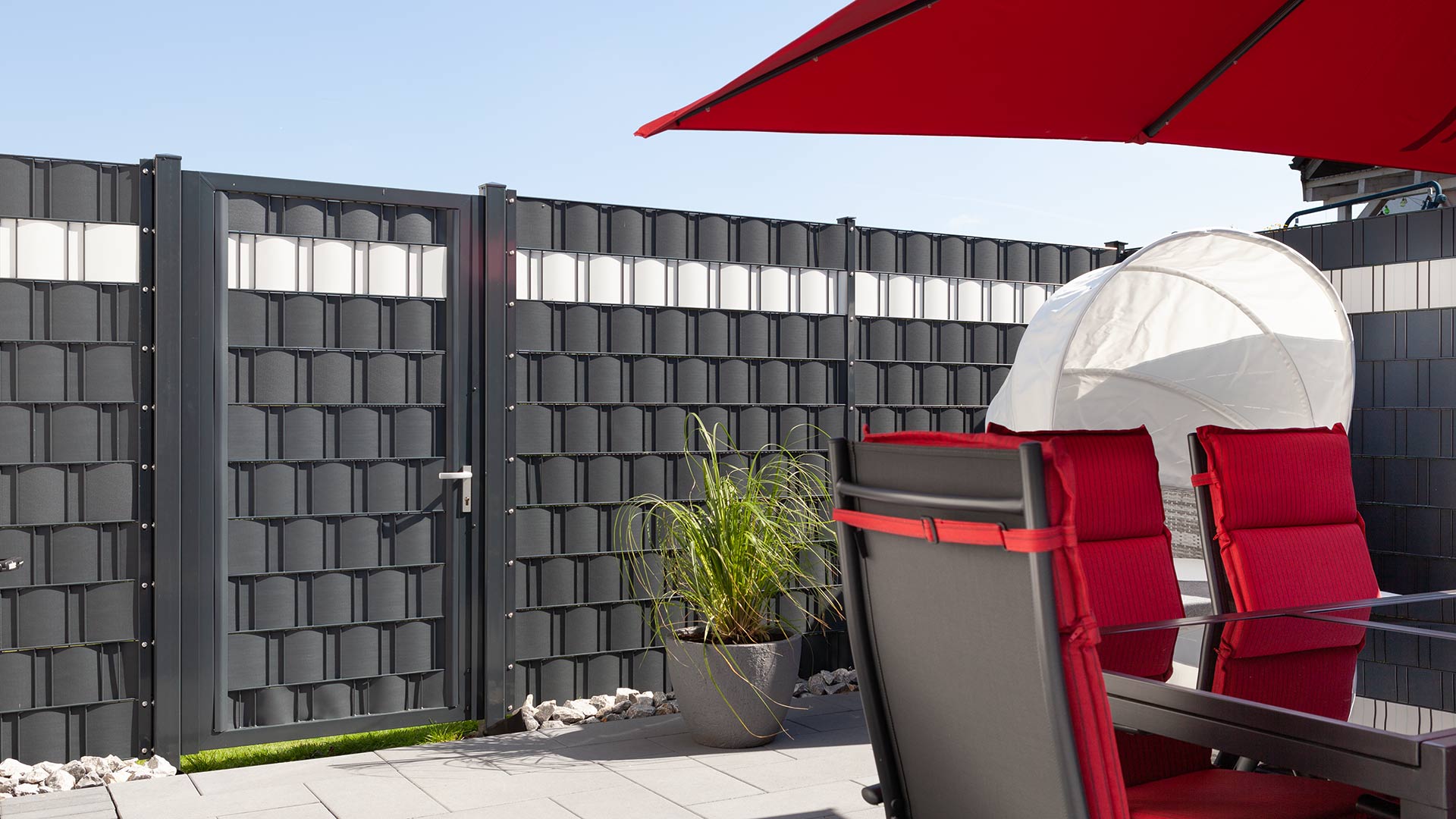 Terrasse hinter einem Doppelstabmattenzaun mit eingezogenem Sichtschutz in Anthrazit