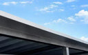 Stirnblech-Verkleidung aus Metall für Trapezblechdach unter blauem Himmel
