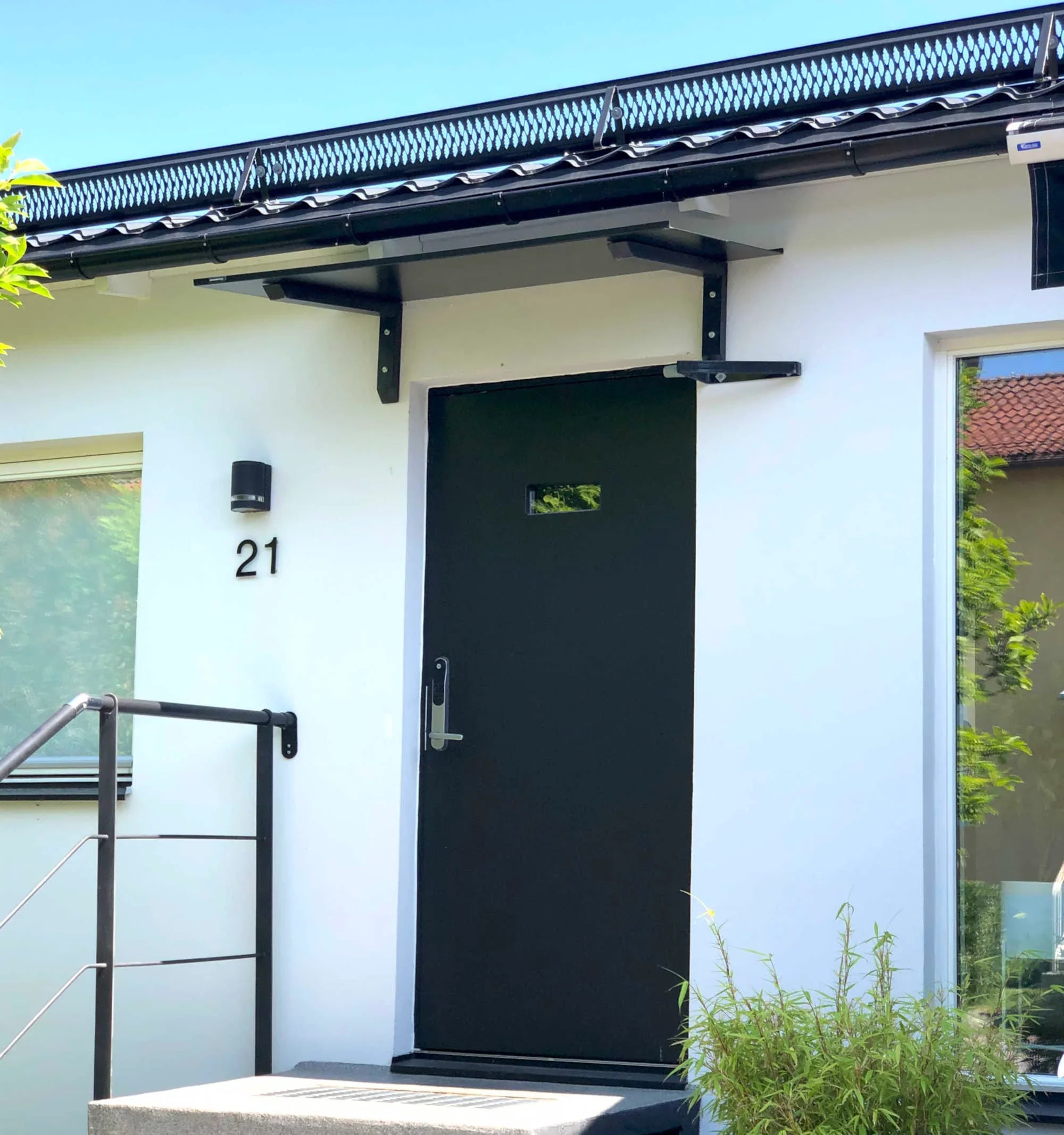 Modernes Vordach aus schwarzem Aluminium mit Konsole über Hauseingangstür, schlichtes Design