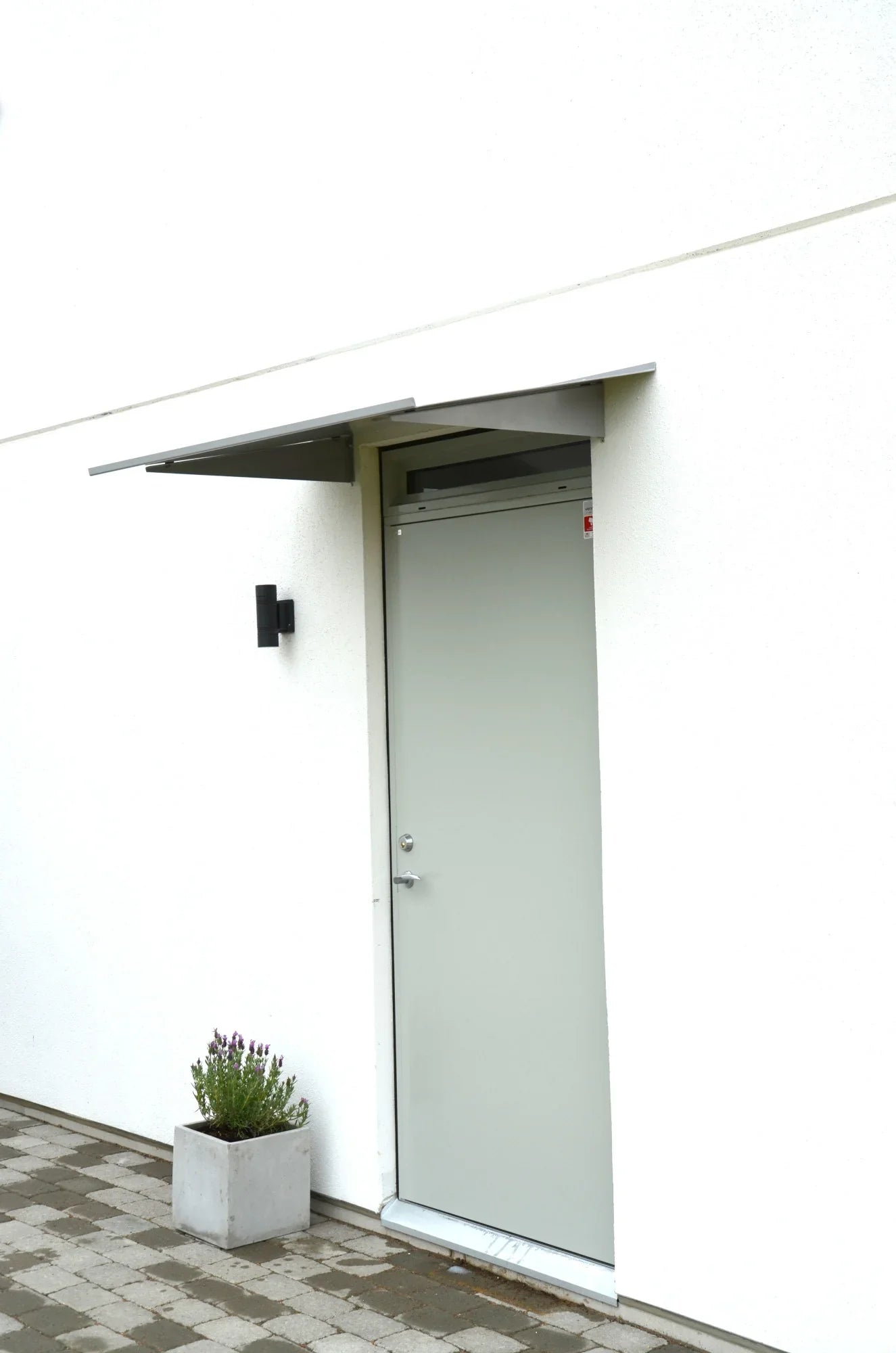 Modernes Vordach aus silbernem Aluminium an weißer Haustür, Konsole an der Fassade