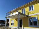 Modernes Metall-Balkongeländer an gelbem Wohnhaus, Edelstahl, eckige Balkonstruktur