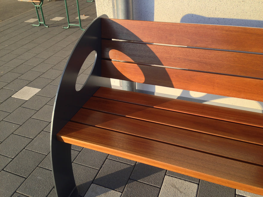 Moderne Sitzbank aus Metall und Holz mit Loch-Design, Outdoor auf Pflastersteinen