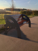 Designer Gartenbank aus Metall und Holz auf gepflastertem Weg im Freien bei Sonnenlicht